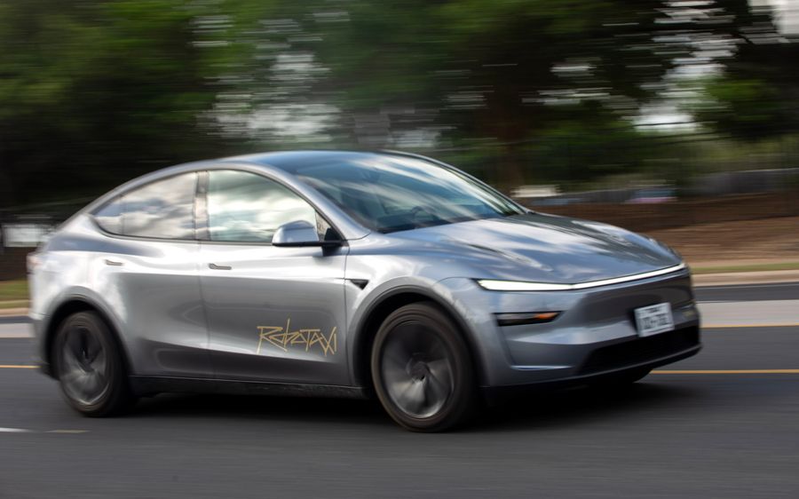一辆标有 RoboTaxi 的特斯拉灰色自动驾驶汽车在道路上行驶。 一辆标有 RoboTaxi 的特斯拉灰色自动驾驶汽车在道路上行驶。